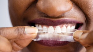 a person using a whitening strip on their teeth