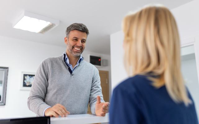 a man speaking with a dental staff member at the front desk