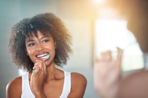 a woman brushing her teeth while looking in a bathroom mirror